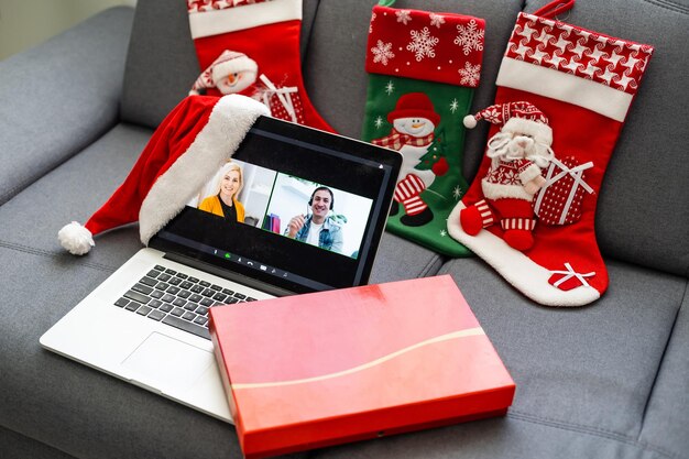 Computer portatile in piedi sul tavolo con regalo e cappello da Babbo Natale in una stanza accogliente, buon Natale e felice anno nuovo