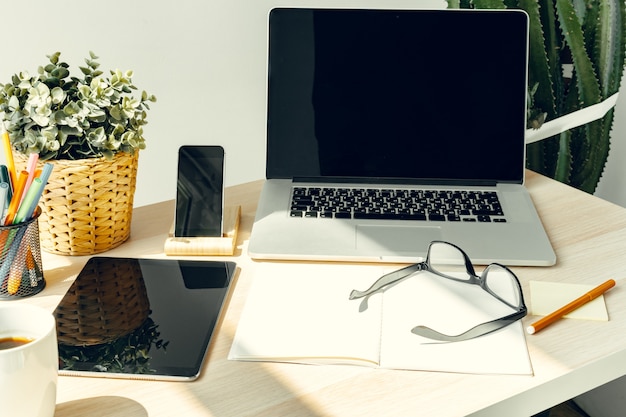 Computer portatile in una stanza leggera sul tavolo di lavoro con articoli per ufficio