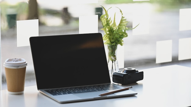 Computer portatile, macchina fotografica, matita e caffè sul tavolo.