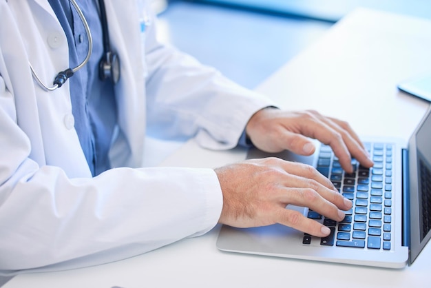 Computer portatile medico e digitazione manuale di e-mail o prescrizione online per cure mediche in una clinica o in ospedale Medicina sanitaria e tastiera con un cardiologo digitare un rapporto di ricerca su Internet