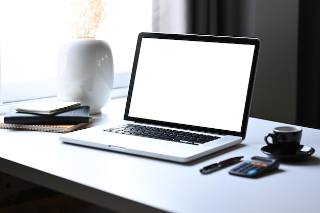 Computer portatile mockup con calcolatrice schermo vuoto e tazza di caffè sul tavolo bianco