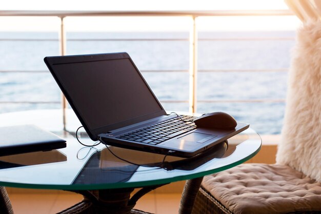 Computer portatile sul tavolo sul balcone dell'hotel con vista mare. Lavoro a distanza, fare affari in vacanza. Internet veloce, comunicazione nei fine settimana. Sempre in contatto. Copia spazio. Modello