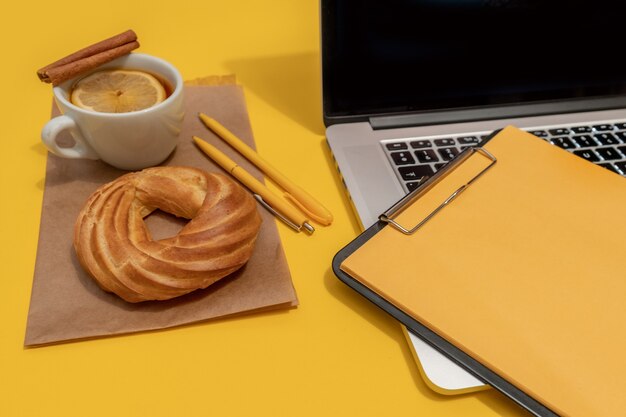 Computer portatile, torta, tazza di tè e appunti, vista dall'alto.