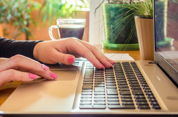 Computer portatile vicino di una tastiera e una tazza di caffè caldo al mattino. Messa a fuoco selettiva