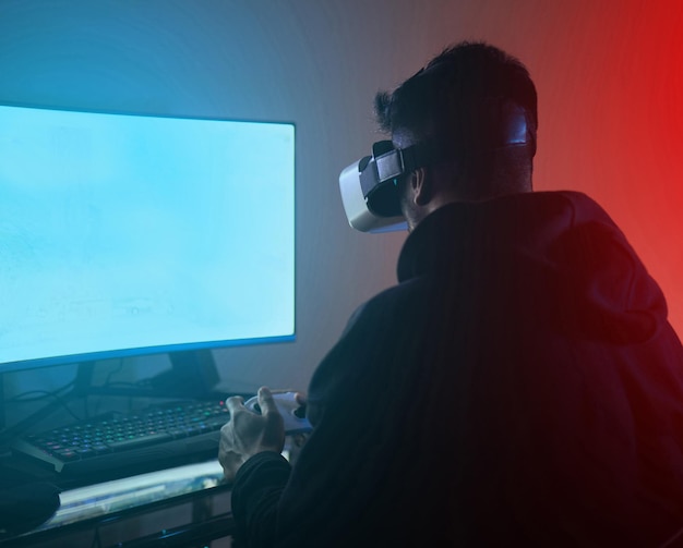 Computer uomo con realtà virtuale su schermo verde e metaverso streaming online di gioco e spazio mockup Mondo digitale Occhiali VR e controller tecnologia futura e streamer maschile in camera oscura