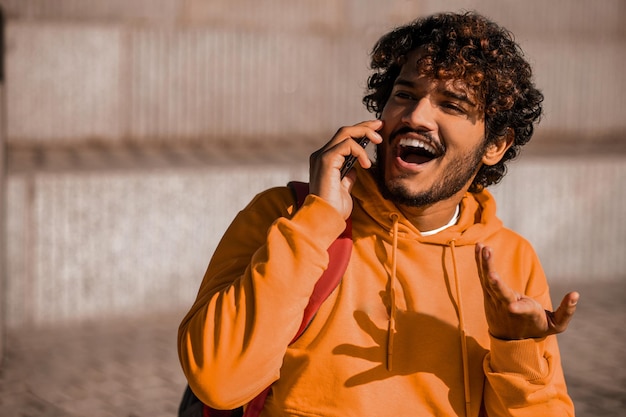 Comunicazione. Giovane in arancione con un telefono in mano