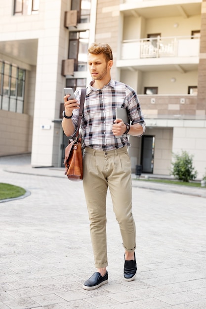 Comunicazione in linea. Piacevole bell'uomo utilizzando il suo smartphone mentre si cammina