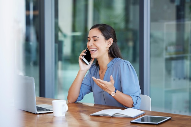 Comunicazione telefonica e risata con una donna d'affari che parla mentre è seduta nel suo ufficio per lavoro Laptop mobile o internet con una dipendente che lavora alla sua scrivania e ride di una battuta