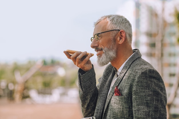 Comunicazione. Un uomo dai capelli grigi con un gadget in mano