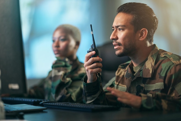 Comunicazione walkie talkie e squadra militare alla stazione con computer che fornisce indicazioni Collaborazione tecnologica e soldati nella stanza dell'esercito o suddivisione con dispositivi radio per il contatto di guerra