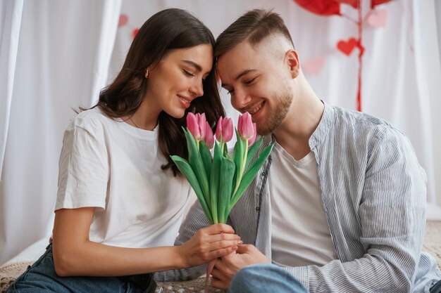 Con bellissimi fiori in mano La giovane coppia è insieme a casa