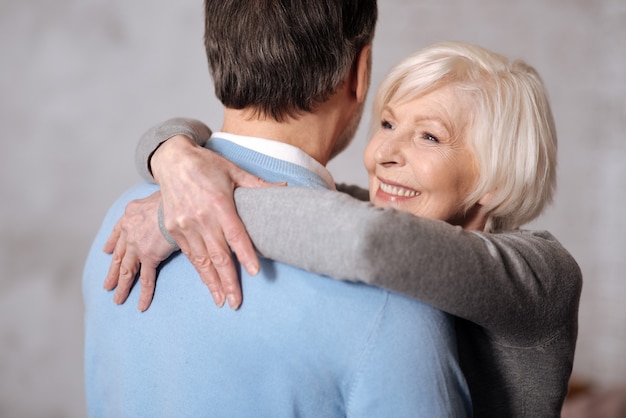 Con grande amore. Ritratto del primo piano di bella donna anziana sorridente che abbraccia il suo marito.