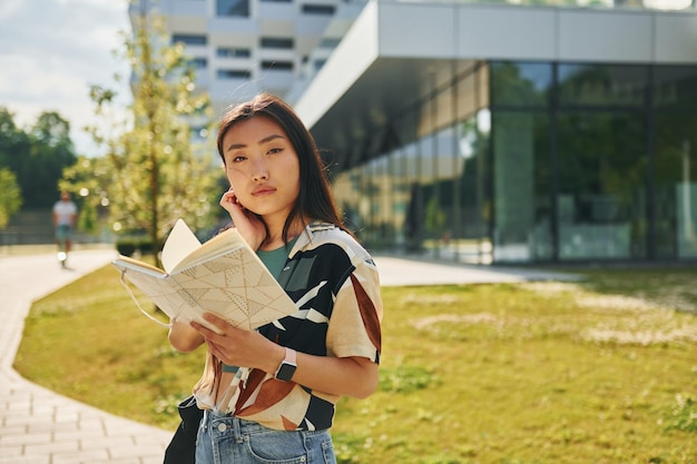 Con il libro in mano La giovane donna asiatica è all'aperto durante il giorno