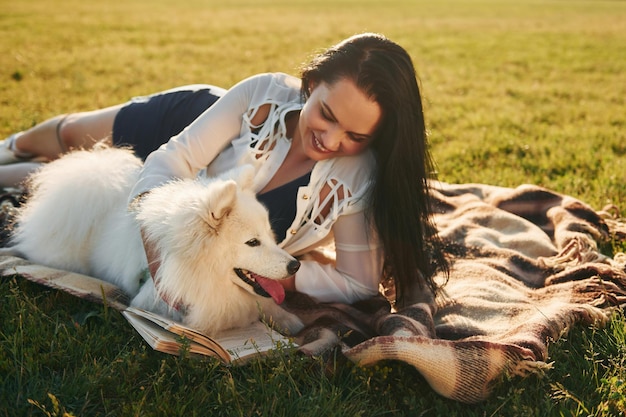 Con il libro La donna con il suo cane si diverte sul campo durante la giornata di sole