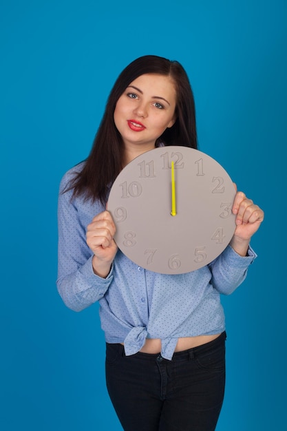 Con l'orologio in mano la donna in blu è in piedi su sfondo blu