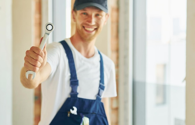 Con la chiave in mano Giovane uomo che lavora in uniforme alla costruzione durante il giorno