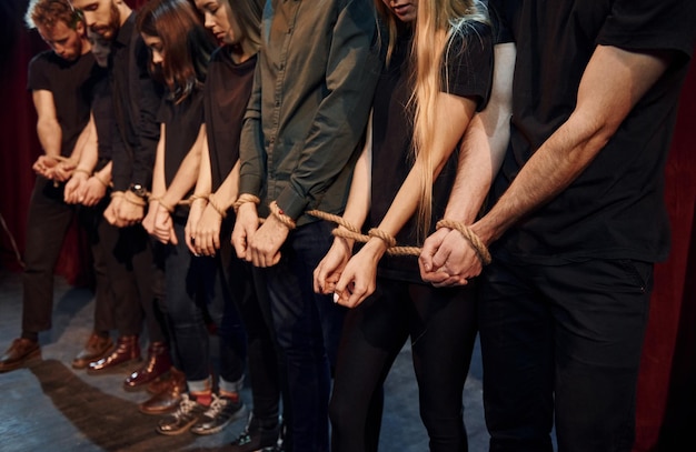 Con la corda in mano Gruppo di attori in abiti scuri durante le prove in teatro