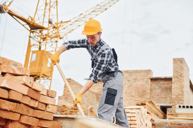 Con la pala in mano L'operaio edile in uniforme e le attrezzature di sicurezza hanno un lavoro sulla costruzione