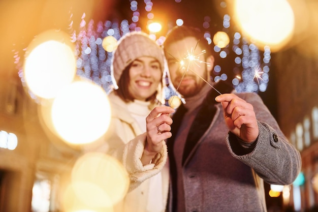 Con le stelle filanti in mano Felice giovane coppia festeggia il nuovo anno all'aperto sulla strada