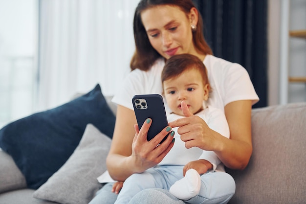 Con lo smartphone in mano la madre con la figlia è a casa insieme