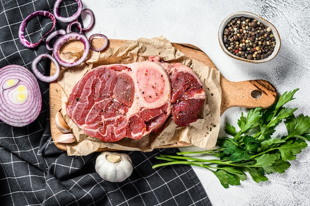 Con ossobuco crudo alle erbe. carne di manzo osso buco. Sfondo nero.