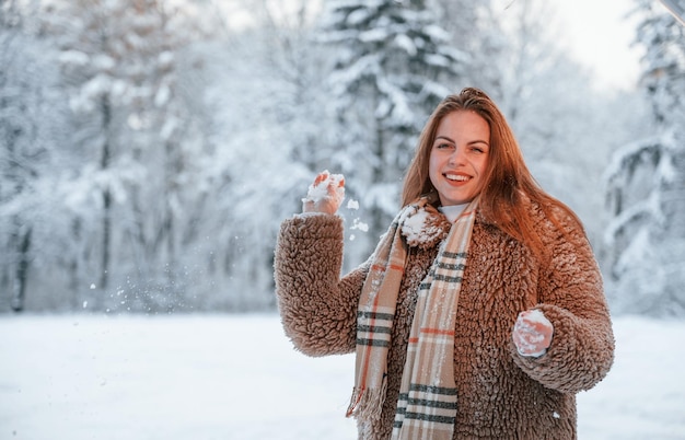 Con palle di neve Bella giovane donna è all'aperto nella foresta invernale