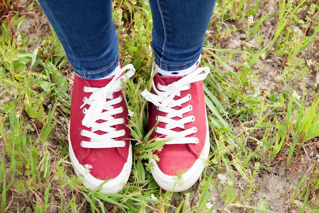 Con scarpe da ginnastica rosse e jeans che calpestano l&#39;erba