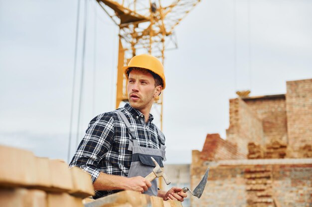 Con spatola per l'edilizia Operaio in uniforme e equipaggiamento di sicurezza ha un lavoro sulla costruzione