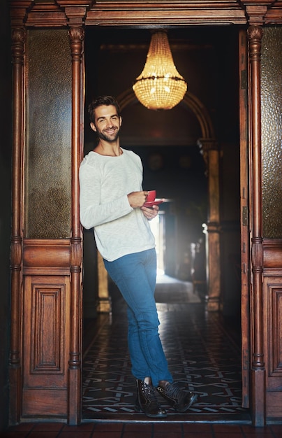 Con una grande tazza di caffè la vita è grande Ritratto di un bell'uomo in piedi sulla soglia di un caffè con in mano una tazza di caffè