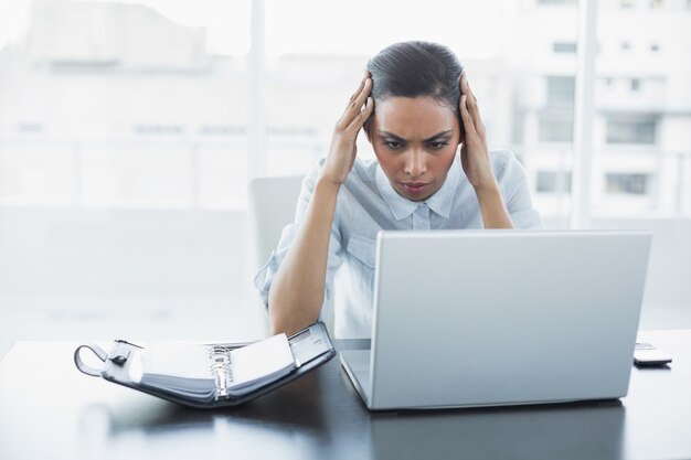 Concentrando la giovane imprenditrice lavorando sul suo computer portatile seduto alla sua scrivania