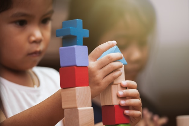 Concentrarsi sulla mano del bambino giocando con blocchi di legno colorati in tonalità di colore vintage