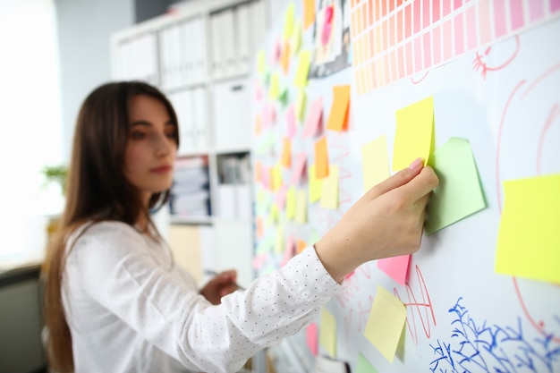 Concentrarsi sulla mano femminile che tiene un pezzo di carta giallo sul bordo del pennarello