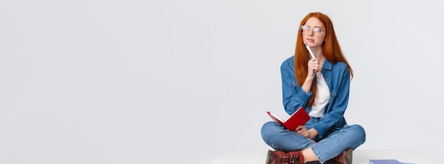 Concentrata, pensierosa e creativa, giovane donna genio con i capelli rossi e gli occhiali.