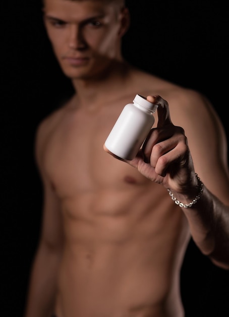 Concentrati sui dettagli un uomo forte e sexy tende la mano con un barattolo bianco su sfondo nero