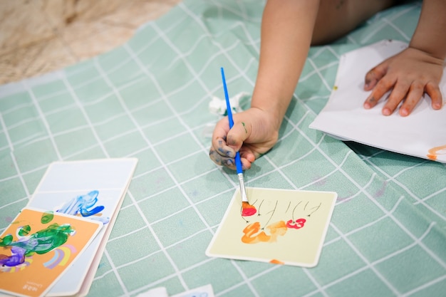 Concentrati sulle mani sulla carta. I bambini usano i pennelli per dipingere acquerelli su carta per creare la loro immaginazione e migliorare le loro capacità di apprendimento.