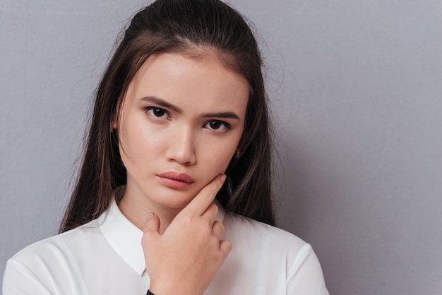 concentrato piuttosto modello asiatico in camicia con la mano sul mento isolato su gray