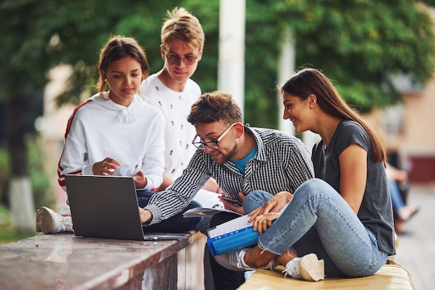 Concentrato sul lavoro. Con laptop. Gruppo di giovani studenti in abiti casual in città durante il giorno.