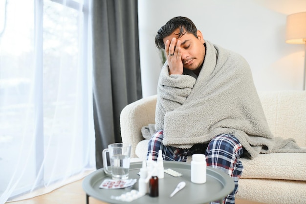 Concept di salute e persone giovane indiano malato in coperta con mal di testa o febbre a casa
