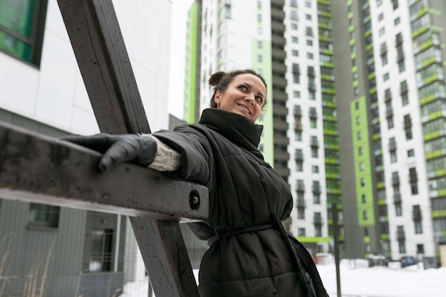 Concept di stile di vita donna bruna spensierata con una giacca da inverno nera che cammina nel cortile della casa