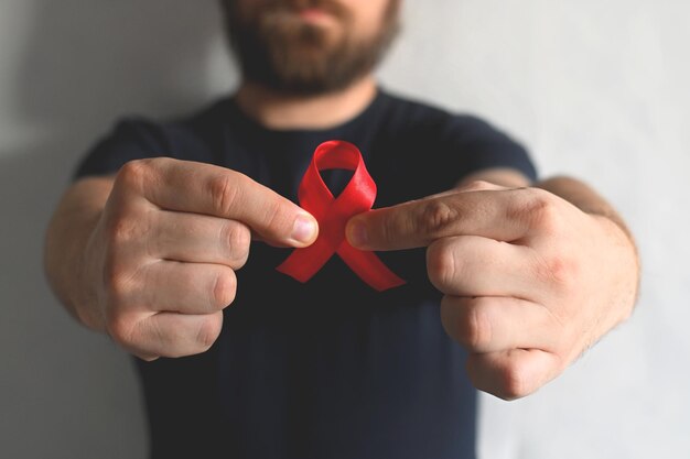 Concept World AIDS e hiv day Un uomo con una maglietta nera tiene un nastro rosso Trasfusione di sangue