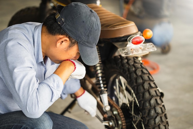 Concetti di riparazione e manutenzione Uomo che ripara la motocicletta in officina Riparazione meccanica della moto nel garage dell'officina