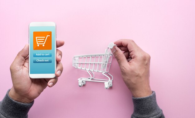 Concetti di shopping online con persona e piccolo carrello e smartphone