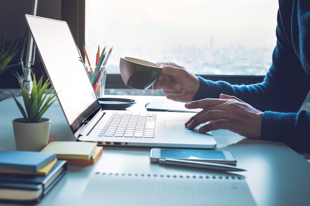 Concetti di vita in ufficio con persona che beve caffè e utilizza il computer portatile sulla finestra vista