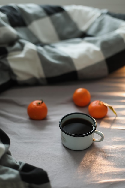 Concetto accogliente invernale Tazza con caffè e mandarini sul letto Spazio copia Vista dall'alto piatta