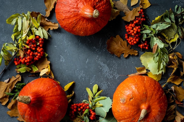 Concetto autunnale con una zucca su uno sfondo scuro con foglie autunnali che celebrano halloween e