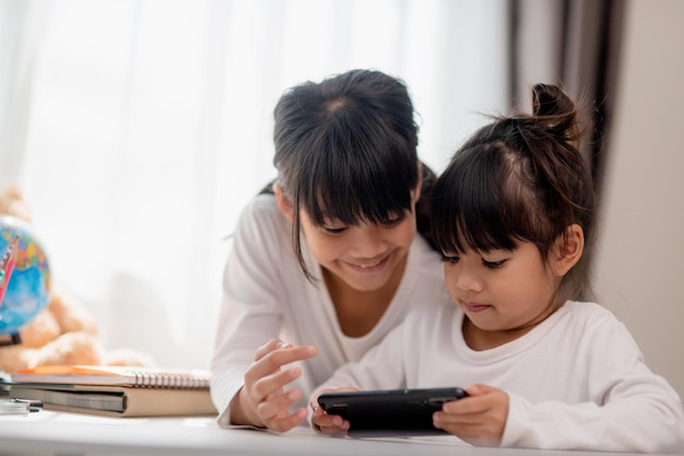 Concetto bambini e gadget Due bambine fratelli sorelle guardano il telefono e sorridono Tengono in mano uno smartphone guarda video impara gioca parla online Internet per bambini Controllo parentale