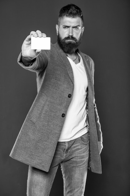 Concetto bancario e di credito Carta bancaria in plastica Credito di denaro facile Quale carta bancaria facile da ottenere Acquisti facili La carta di credito ti dà libertà e fiducia Uomo hipster con la barba in possesso di una carta bianca di plastica