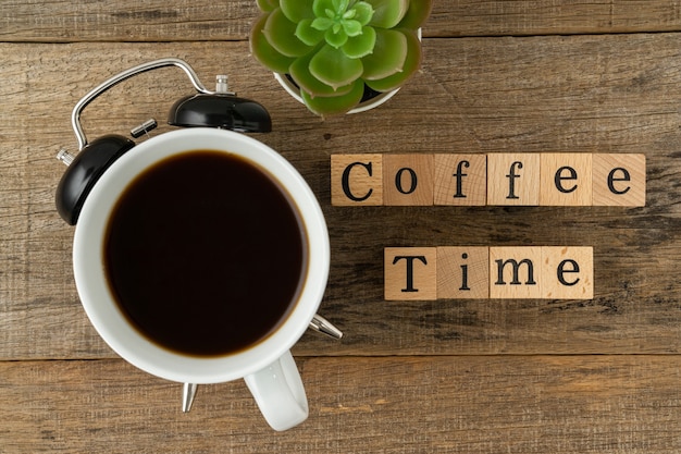 Concetto creativo una tazza di caffè e testo tempo del caffè su sfondo di legno
