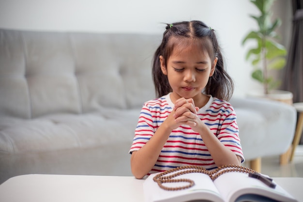 Concetto cristiano Bambina asiatica che prega trattenendo la croce Concetti di speranza fede Cristianesimo religione