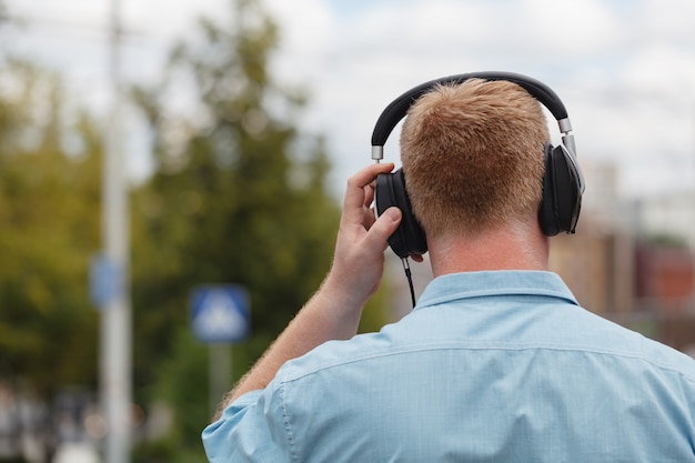 Concetto d'ascolto di camminata delle cuffie di musica dell'uomo